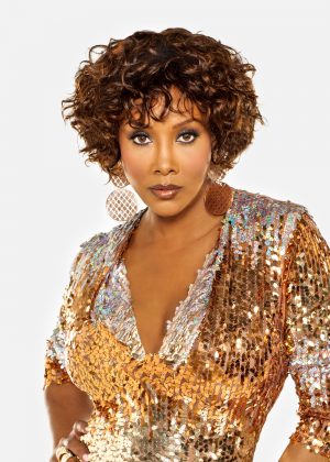 A woman with curly hair wearing a gold dress.